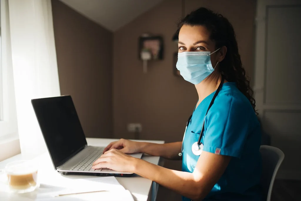 Doctora trabajando en su computadora y mirando a cámara