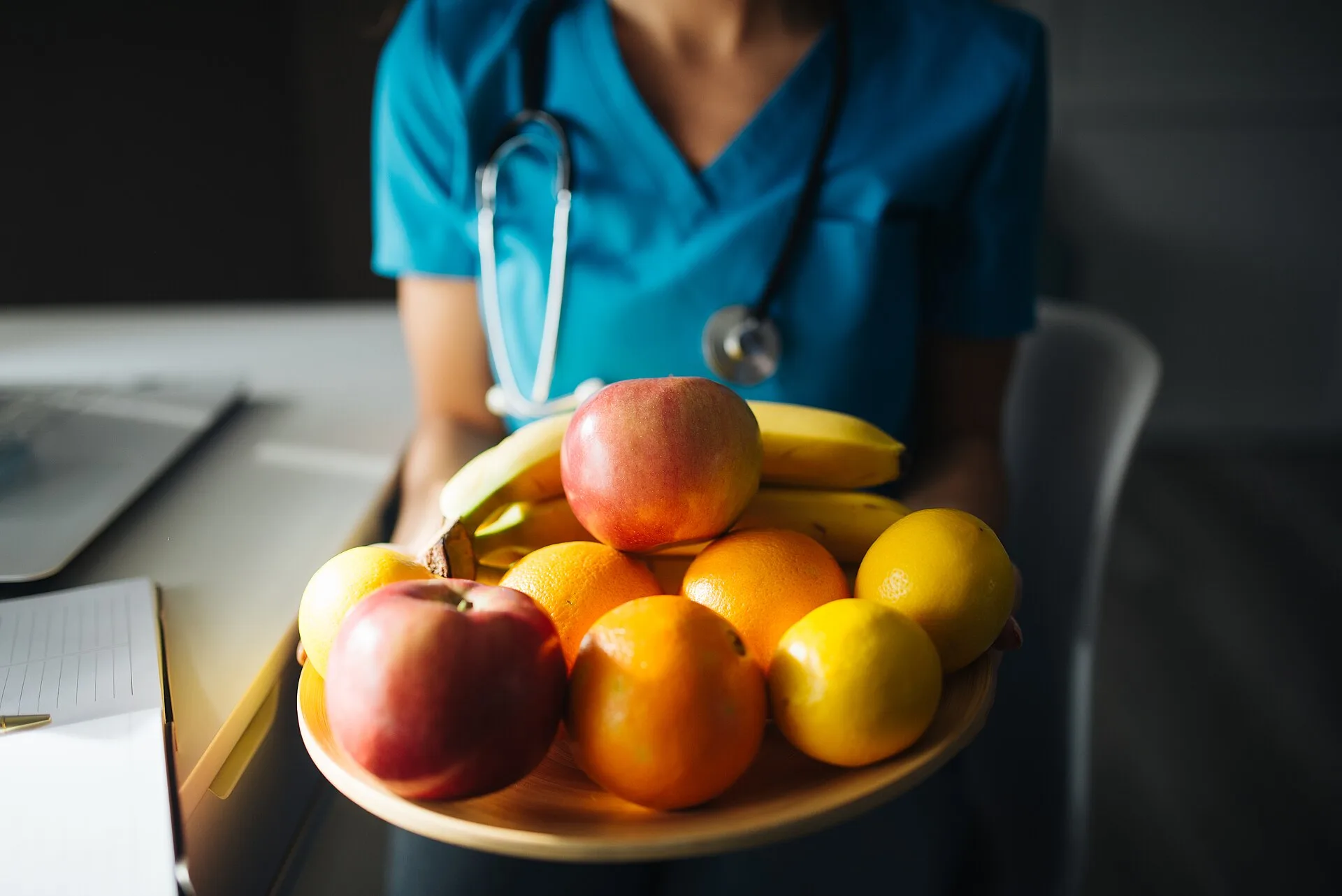 Doctora sostiene un plato con fruta fresca